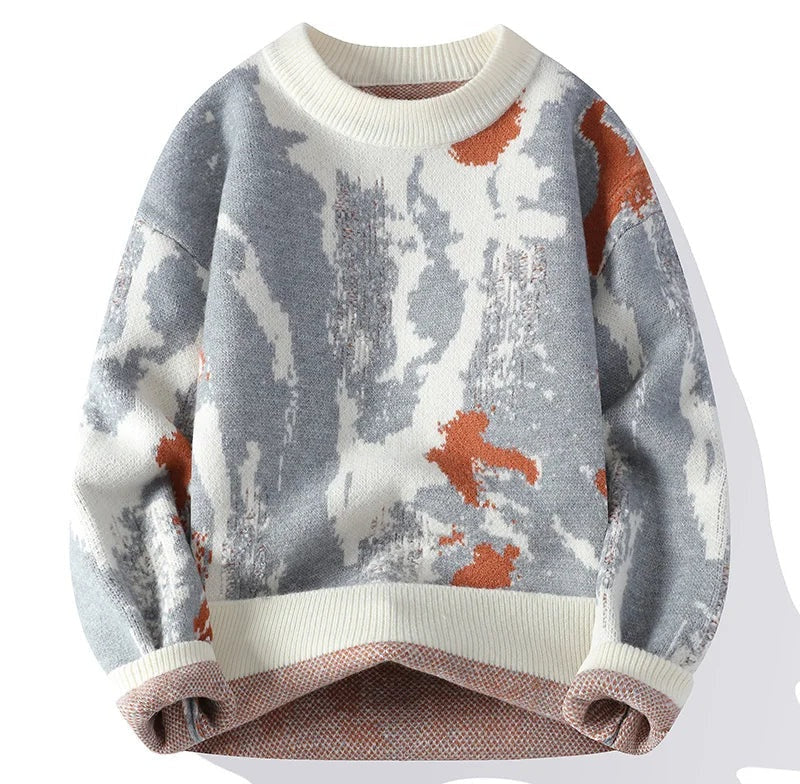 Knit sweater with abstract gray and white pattern and orange accents, cream ribbed crew neck and cuffs seen from the front