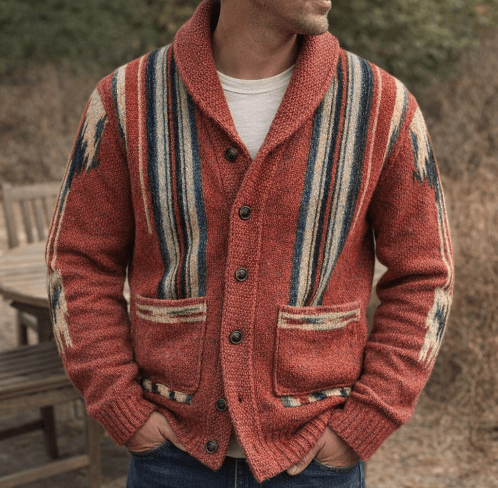 Person wearing a red jacquard knit cardigan with striped panels, button front and two front pockets outdoors