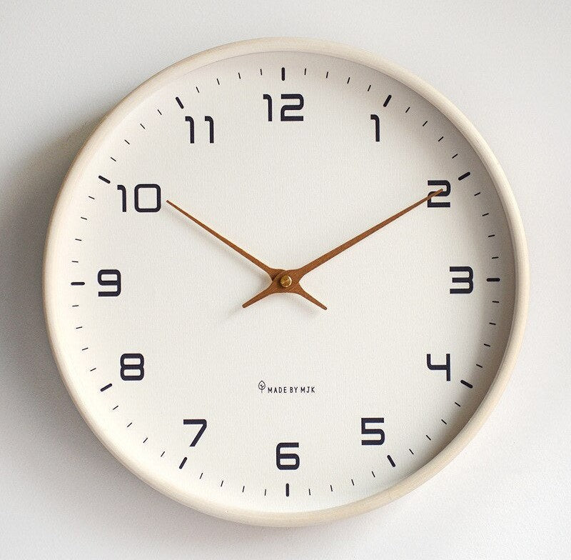 Round wall clock with a neutral beige frame, white dial, black Arabic numerals and brown slender hands
