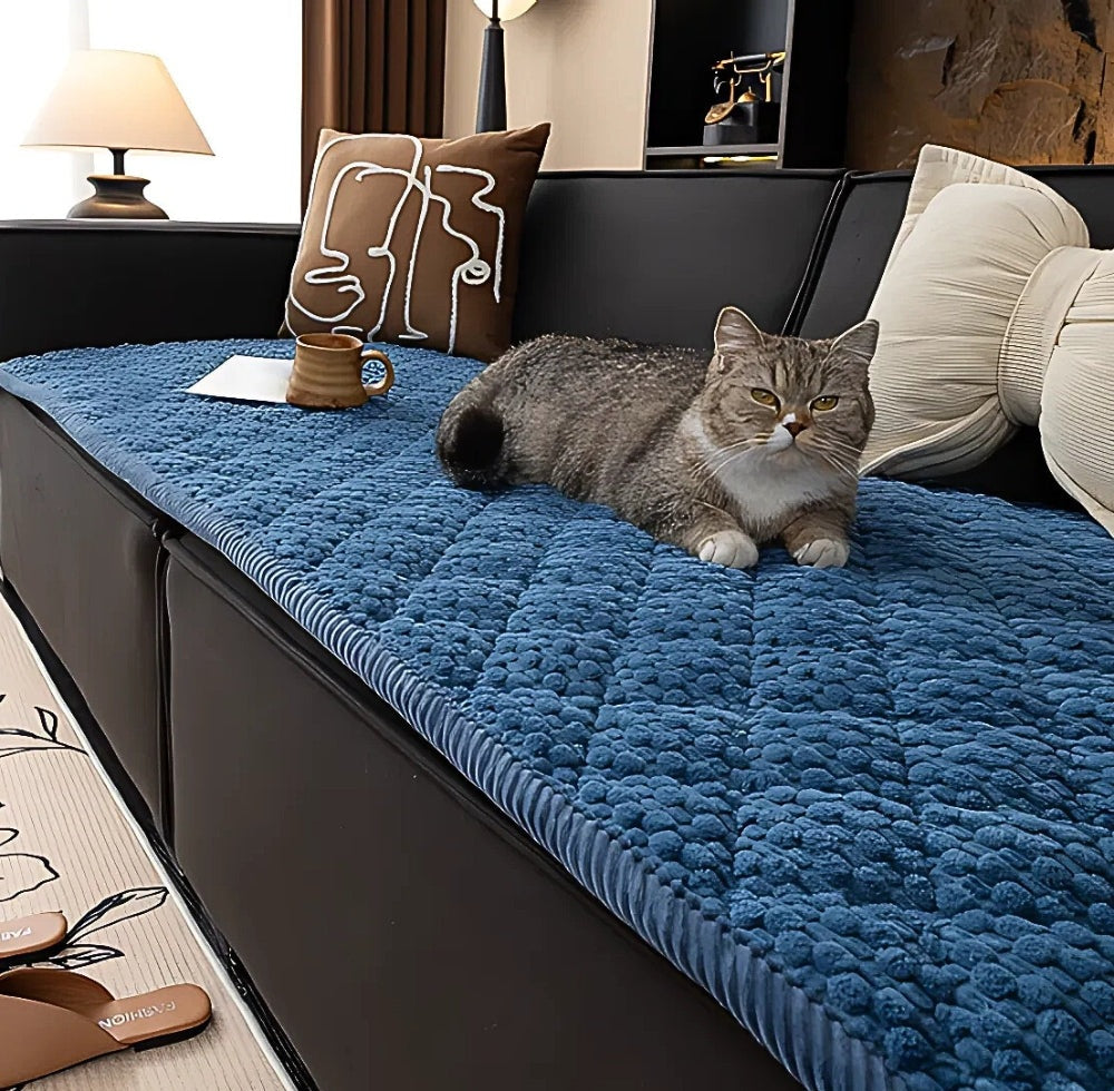 Blue textured microfiber sofa protector slipcover on a black couch with a cat lying on it and beige pillows nearby