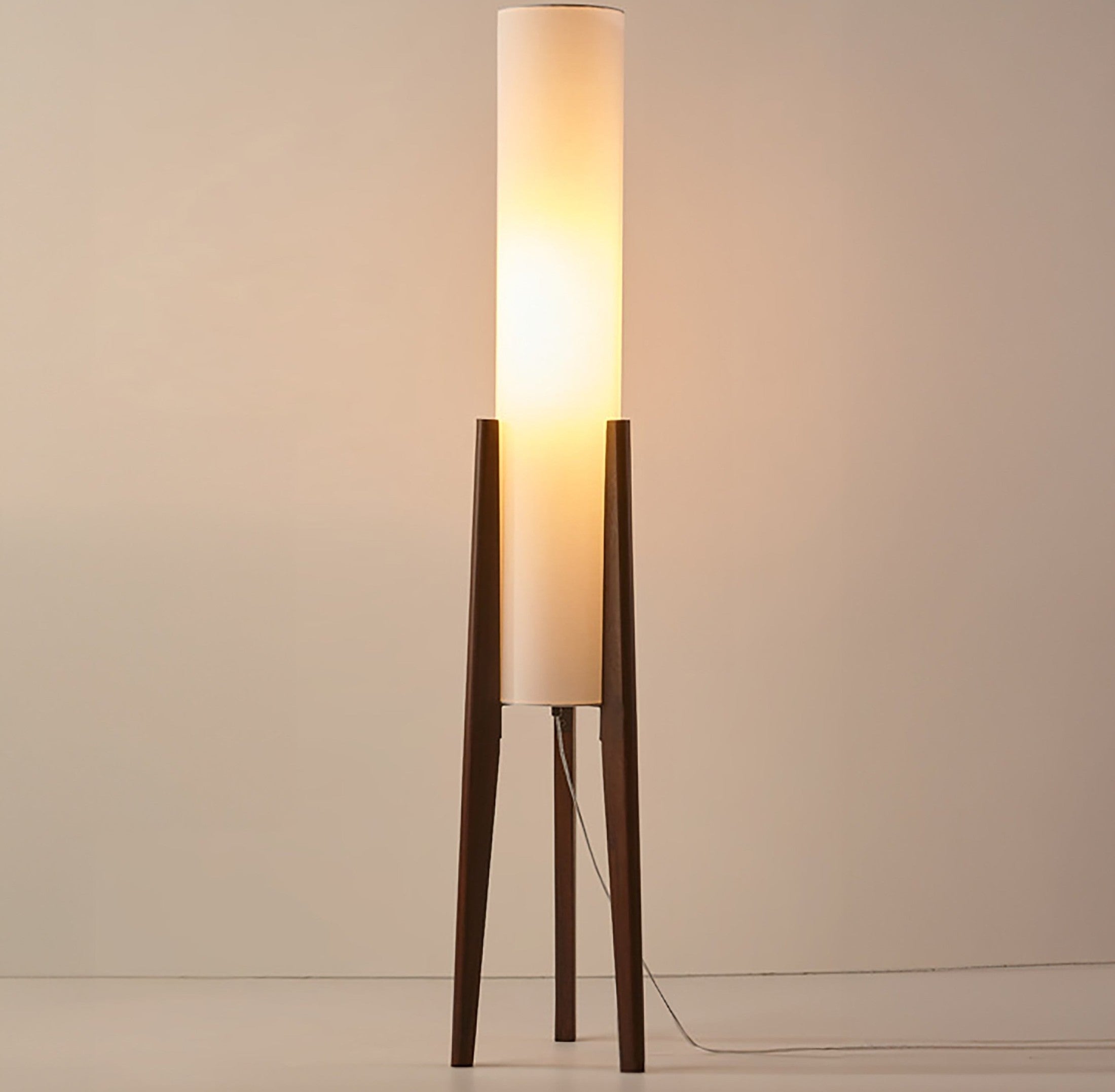 Japandi style floor lamp with a tall white fabric shade supported by solid walnut tripod legs and a visible power cord
