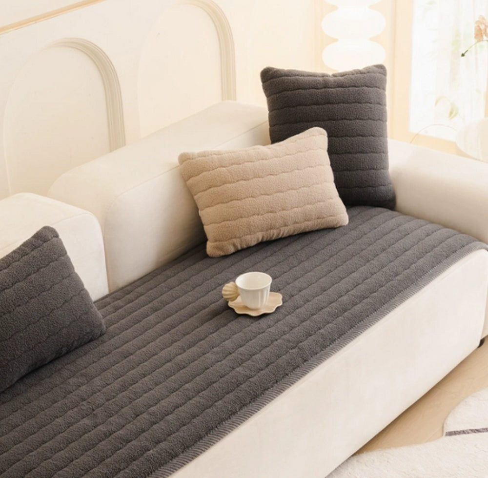 Lunara plush sofa cover in dark gray with a ribbed texture on a light sofa, with beige and dark gray cushions and a small cup on a flower shaped saucer.