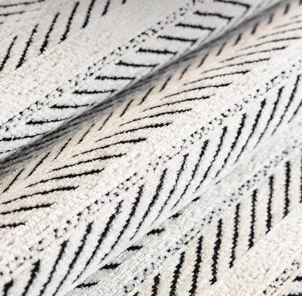 Close up of cream microfiber fabric with black herringbone pattern and a folded edge