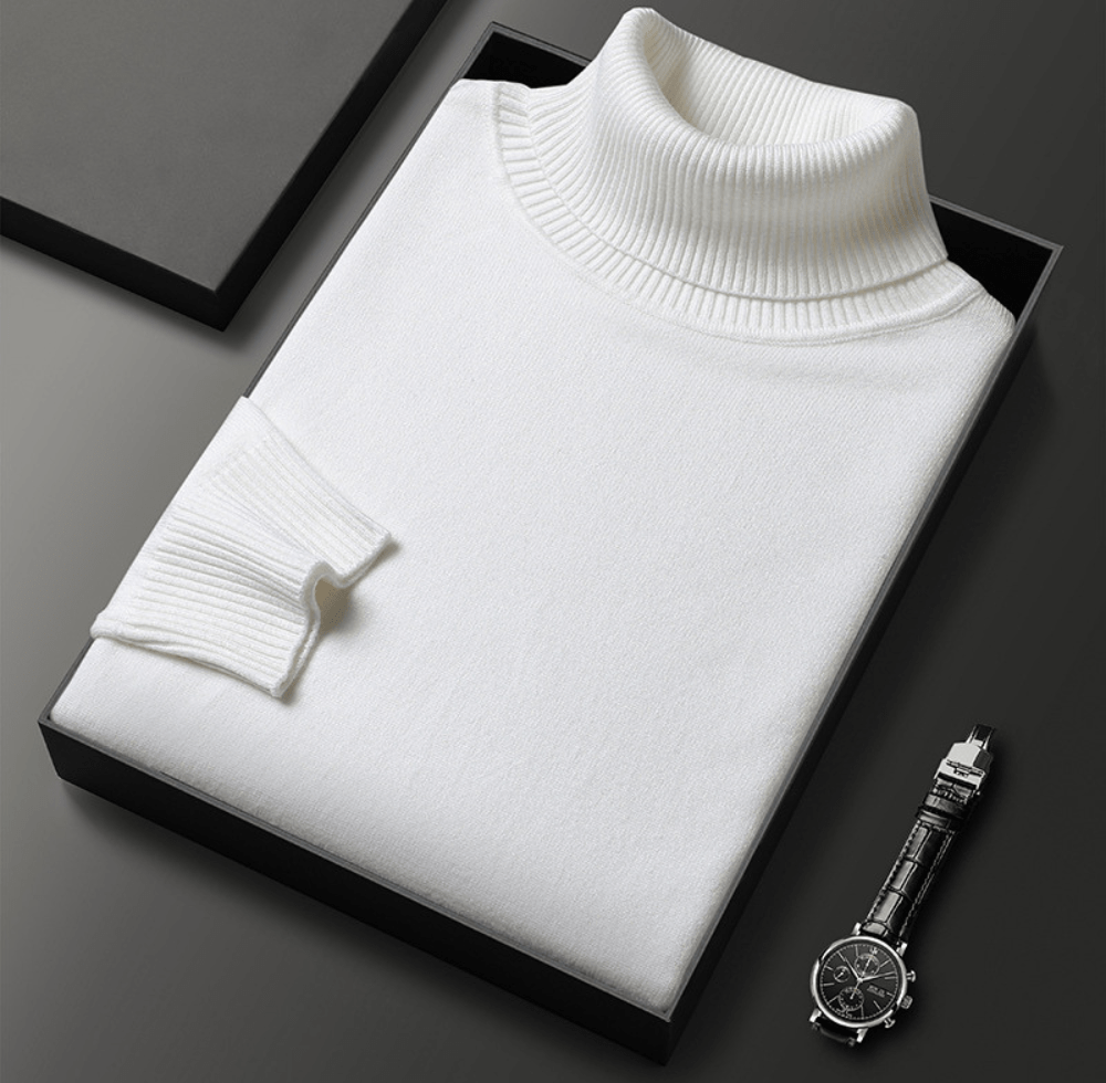 White Montclair cashmere turtleneck sweater with ribbed collar folded in a black box beside a silver wristwatch on a dark surface
