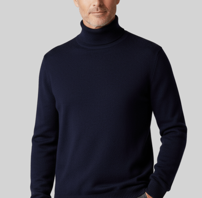 Man wearing a navy blue cashmere turtleneck sweater with a ribbed collar against a light gray background