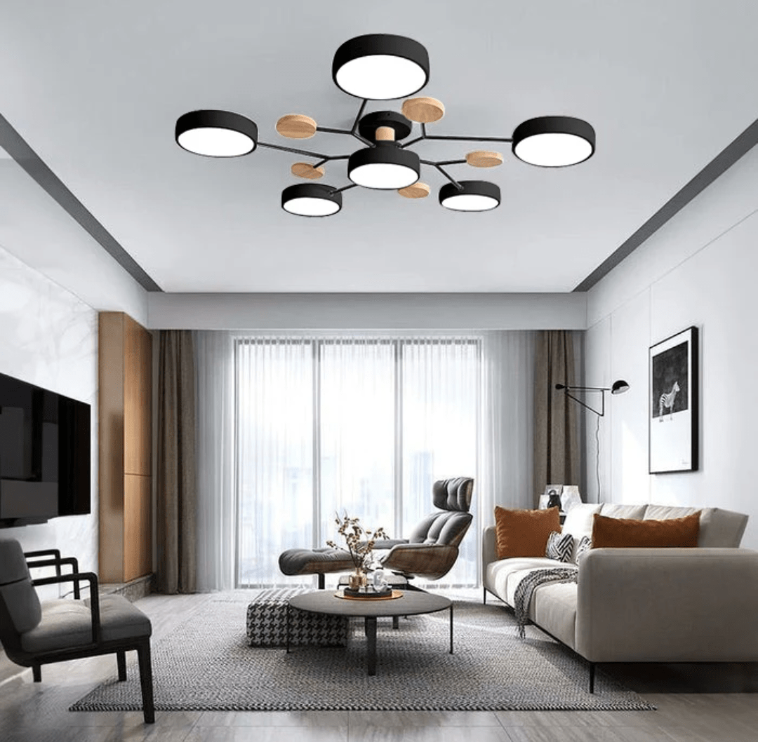 Nordhaven LED ceiling light with black metal arms and wooden accents in a modern living room above a beige sofa and round coffee table