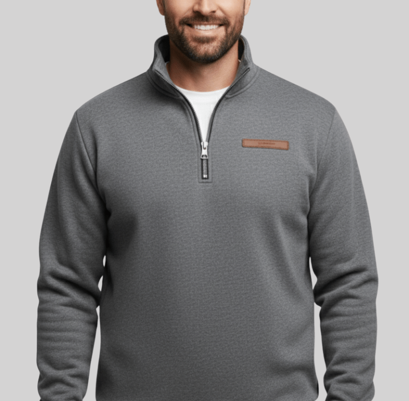 Man wearing a gray half zip fleece sweater with a stand up collar and a small brown leather patch on the left chest