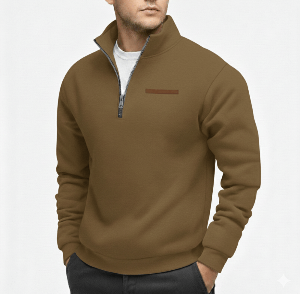 Man wearing a brown half zip sweater with a zip collar and a small rectangular chest patch over a white shirt.