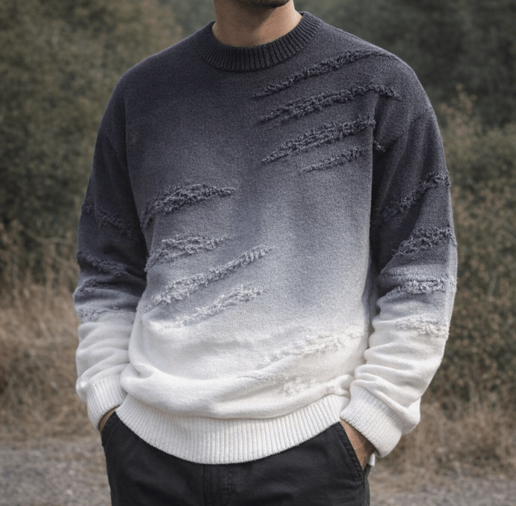 Ombra gradient knit crewneck sweater with distressed patches in a dark navy fading to white worn by a person outdoors