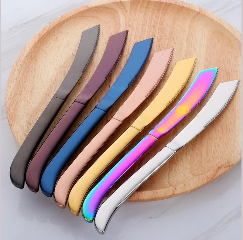 Seven serrated kitchen knives with colored curved handles arranged on a round wooden cutting board