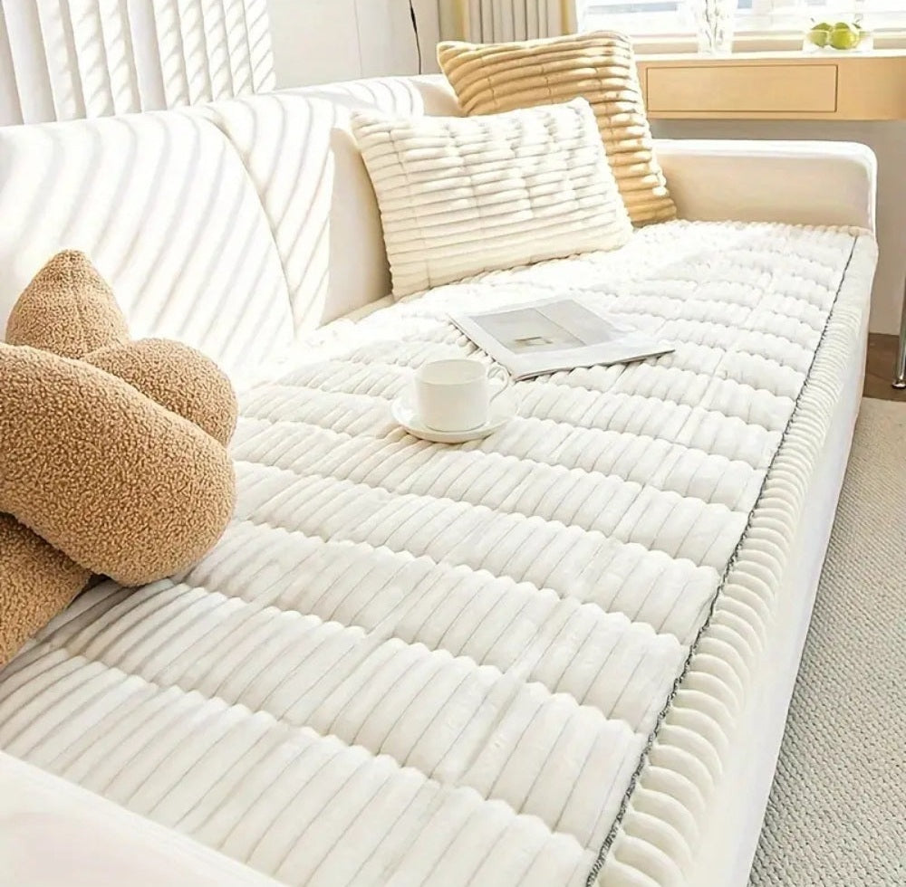 White sofa with a Veloura microfiber cover featuring plush flannel and hand pleated edges, with white and beige pillows and a cup on a saucer and a magazine placed on the cover