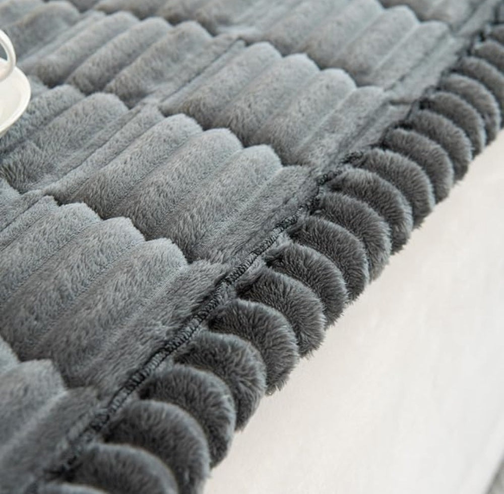 Close up of a gray plush sofa cover with hand pleated edges and soft microfiber texture