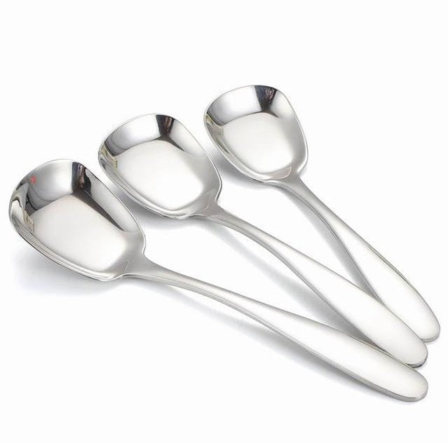 Three polished stainless steel serving spoons with long handles arranged on a white background