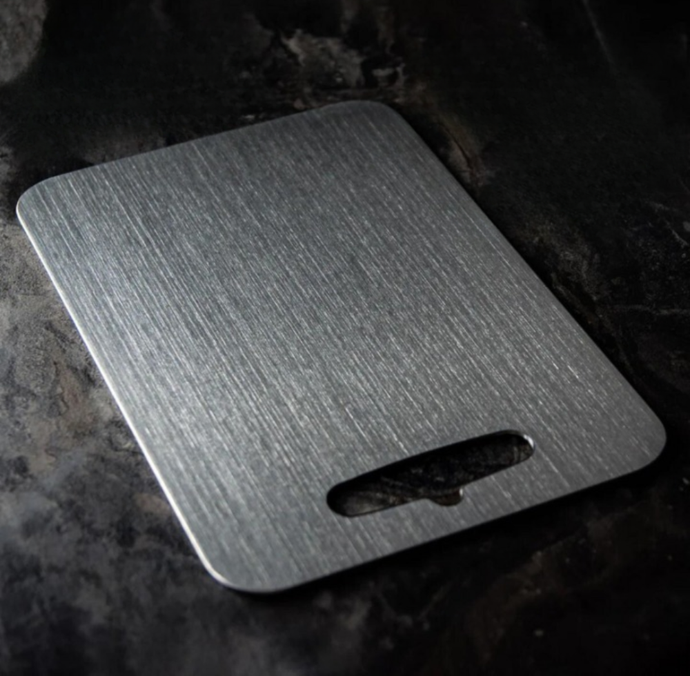 Aegis titanium cutting board with a brushed non porous surface, rounded corners and an elongated oval hanging slot