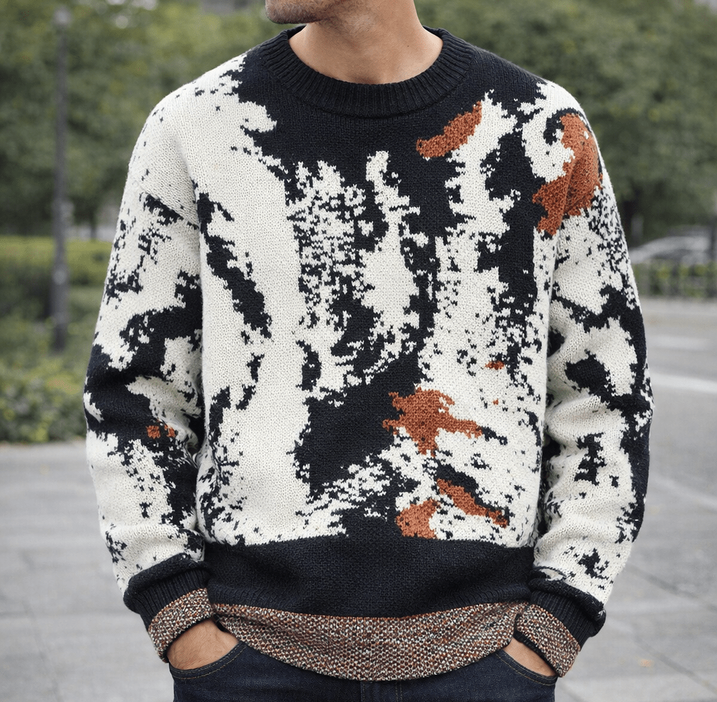 Person wearing a black and white abstract knit sweater with brown patches, crew neck, and ribbed cuffs and hem outdoors