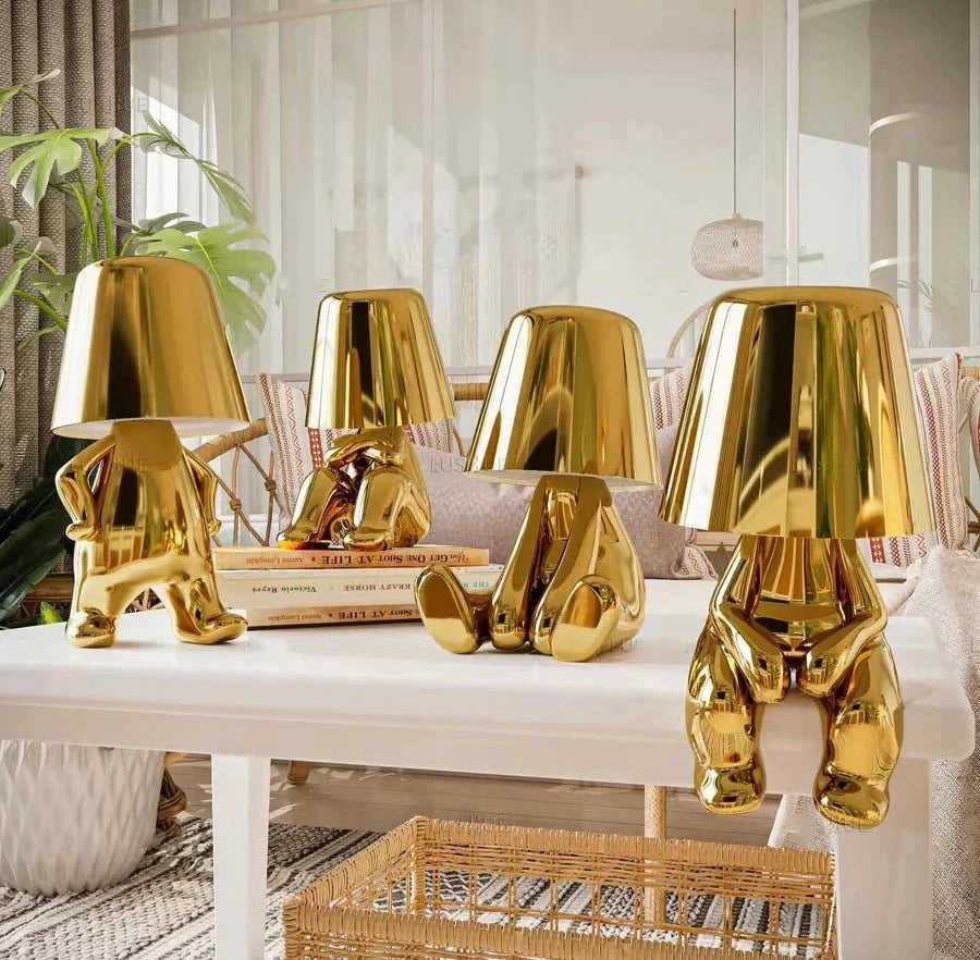 Glossy gold metal lamp shades and decorative gold sculptures on a white coffee table in a bright living room