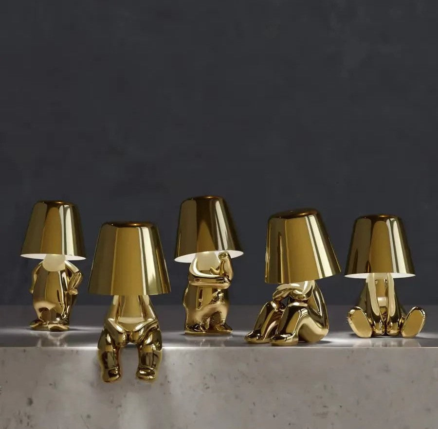 Five gold aluminum table lamps with frosted glass shades arranged along a marble surface against a dark wall