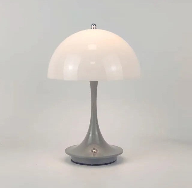 White dome lampshade on a gray curved stem forming a table lamp with a circular base and a small round switch