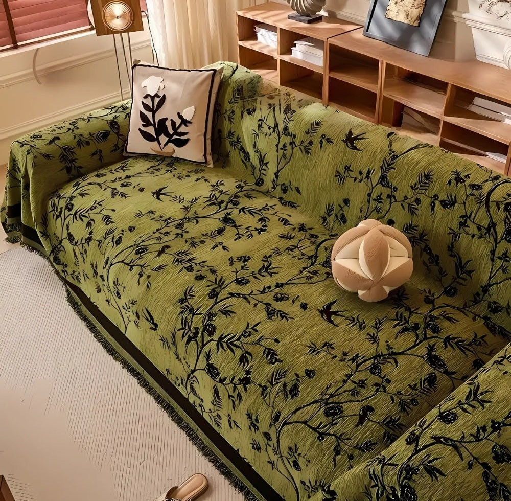 Green chenille sofa cover with black floral vine jacquard pattern and tassel trim on a living room sofa