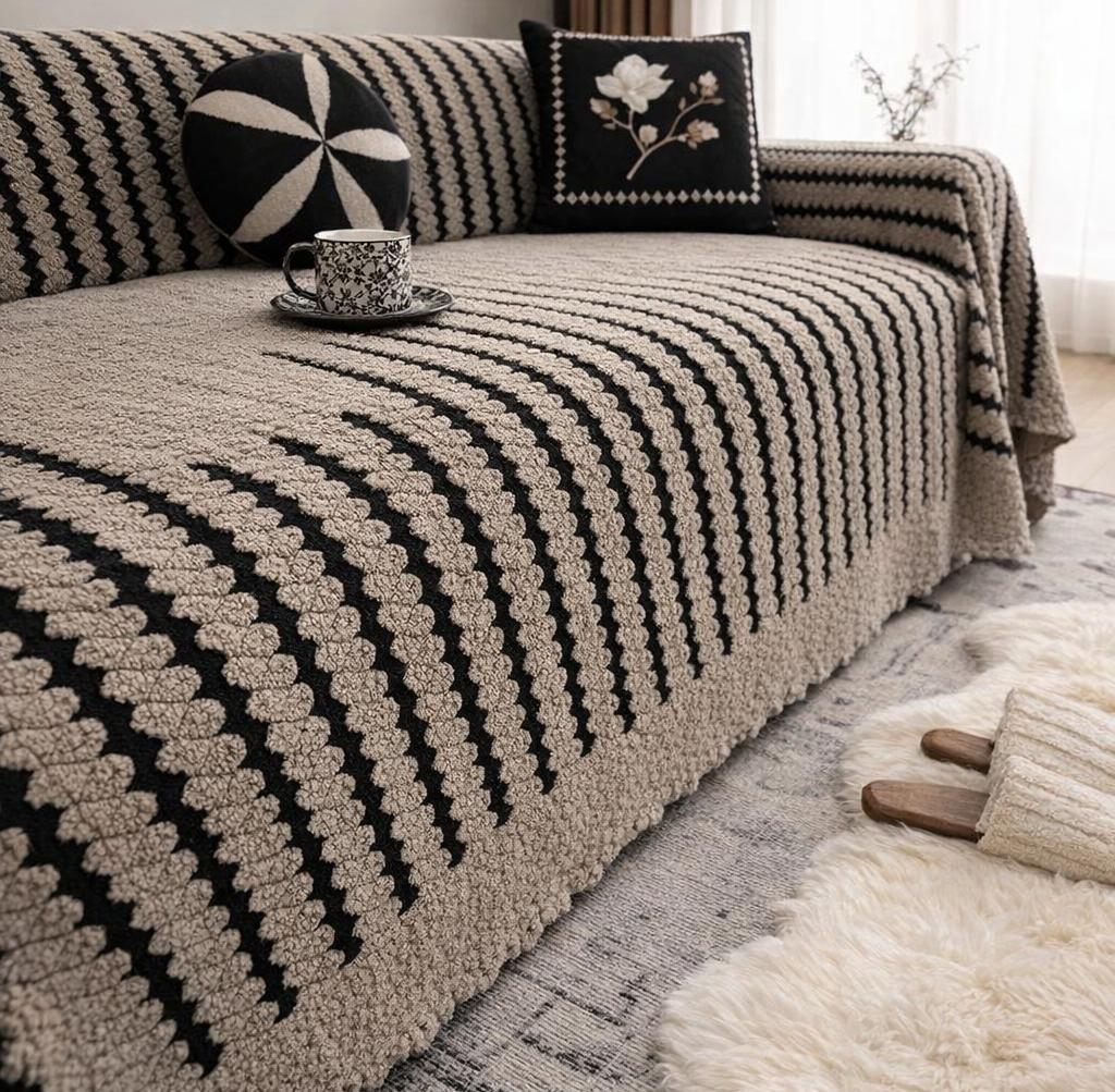 Briarhaven plush microfiber blend sofa cover with a tufted linear design in beige and black on a striped sofa with decorative pillows and a cup on a saucer nearby