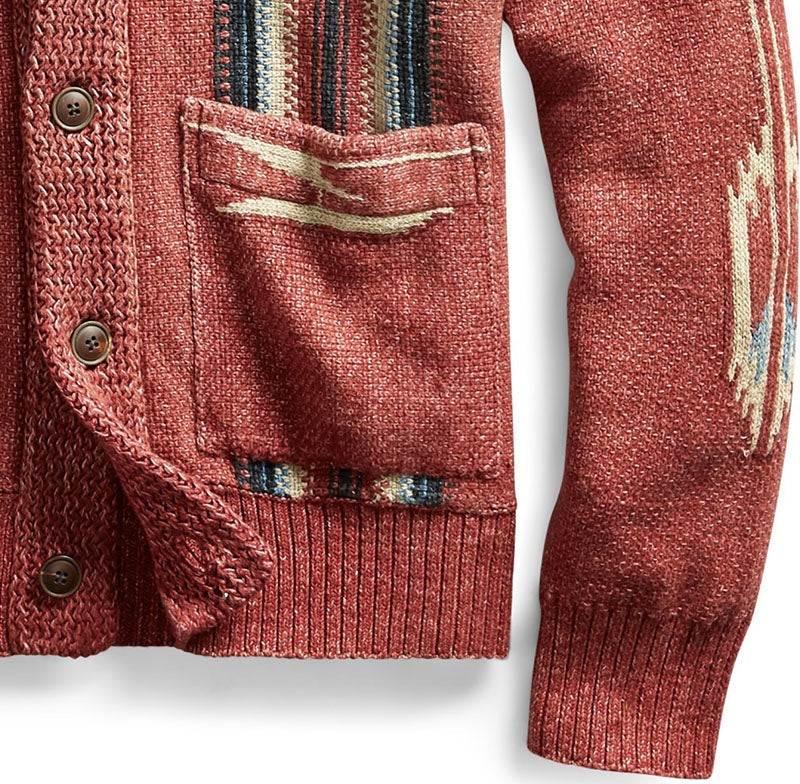 Close up of red jacquard knit cardigan with a small front pocket, visible brown buttons, striped trim and ribbed hem and cuffs.