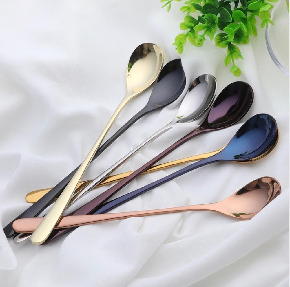 Dubai dessert spoons plated stainless steel with sleek modern handles in gold silver black blue and rose gold laid on white fabric