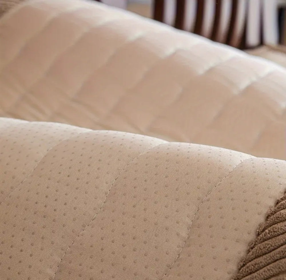 Beige plush sofa cover fabric with a small dot pattern and quilted curved stitching visible on a sofa