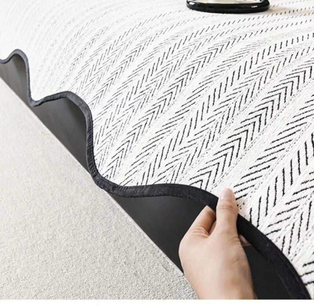 Close up of a white and black herringbone sofa cover with scalloped wave edge trim being held by a hand