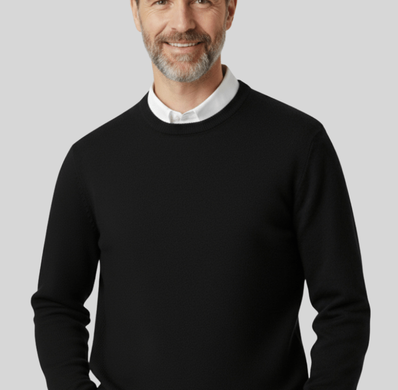 Male model wearing a black knit crewneck sweater with a white collared shirt underneath