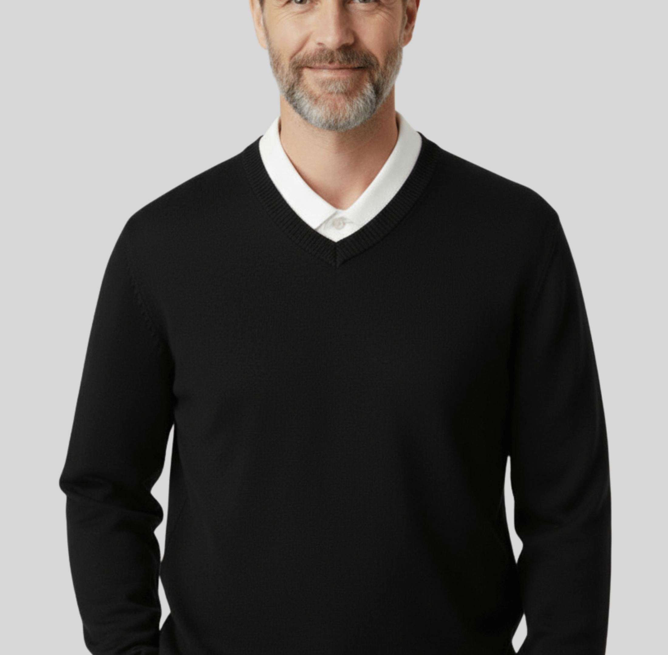 A man wearing a black cashmere V neck pullover sweater with a white collared shirt underneath