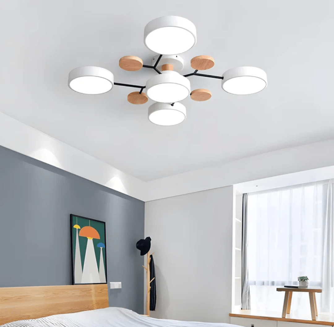 Nordhaven LED ceiling light with multiple round white diffusers mounted on black metal arms and wooden accent discs in a modern bedroom with a gray accent wall and a wooden bed
