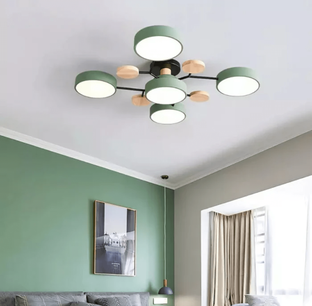 Nordhaven LED ceiling light with green round shade modules connected by black arms and wooden accents on a white ceiling in a living room