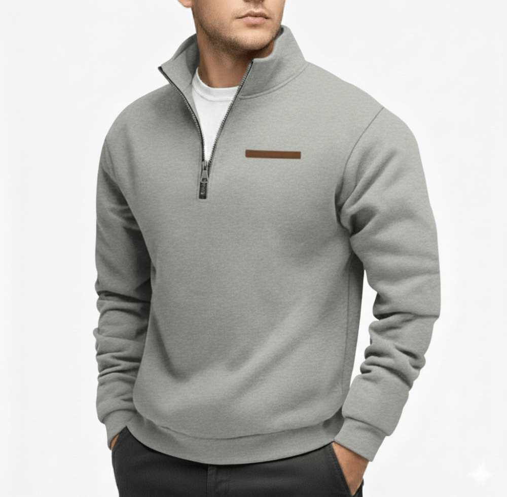Man wearing a light gray half zip fleece sweater with a stand up collar and a small brown logo strip on the chest