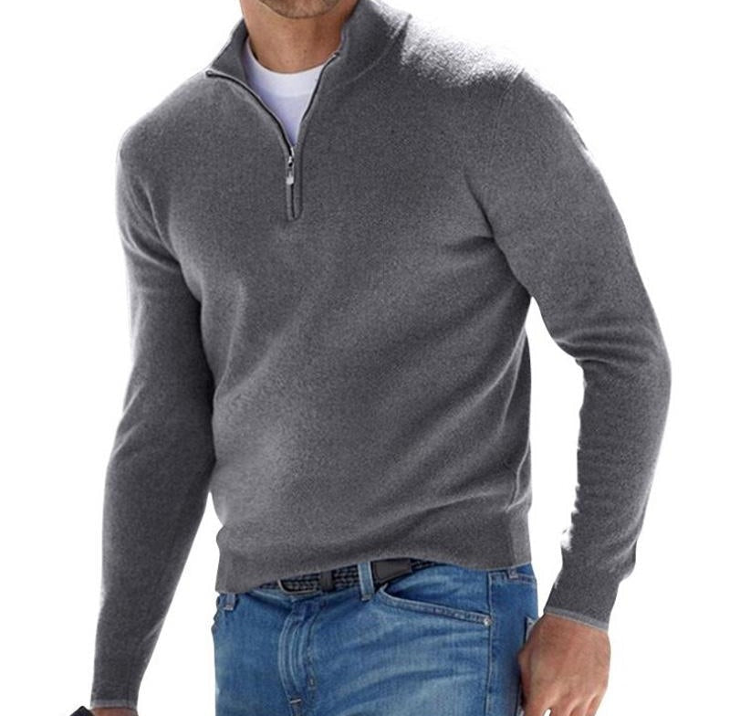 Man wearing a gray solid knit quarter zip pullover sweater with a zipper at the neck and blue jeans