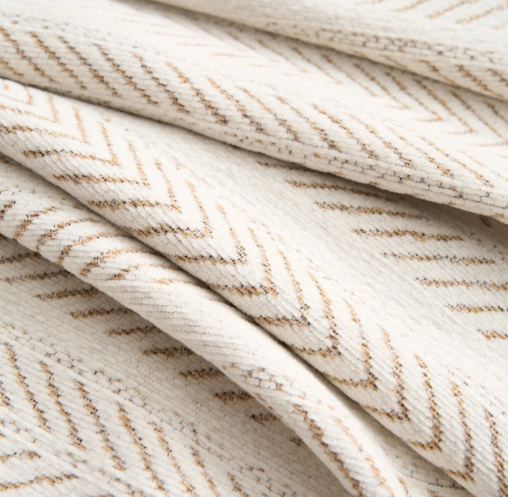Close up of cream herringbone chenille fabric with tan lines folded in soft layers