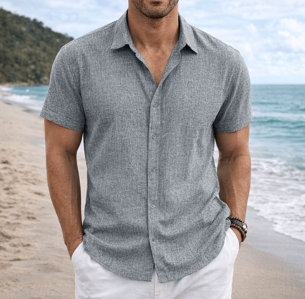 Man on the beach wearing a gray cotton linen short sleeve shirt with a collar and front buttons