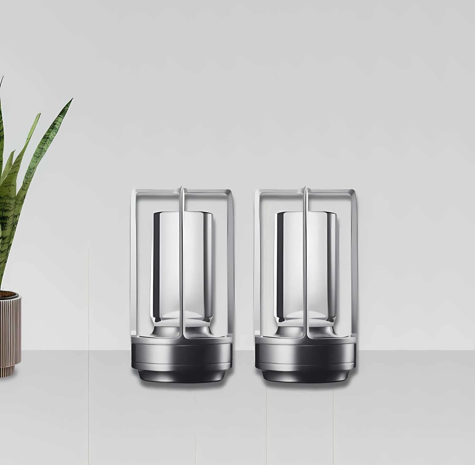 Two cordless lantern table lamps with crystal and metal frames sit on a white countertop, with a potted plant on the left