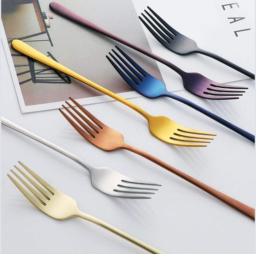Colorful stainless steel forks with a mirror finish arranged diagonally on a white surface.