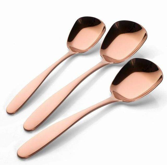 Three rose gold serving spoons with long handles and a polished finish arranged on a white background